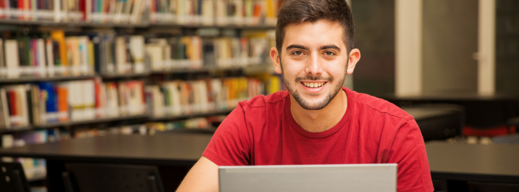 Portrait of an attractive Latin student doing some school work with a laptop in the library